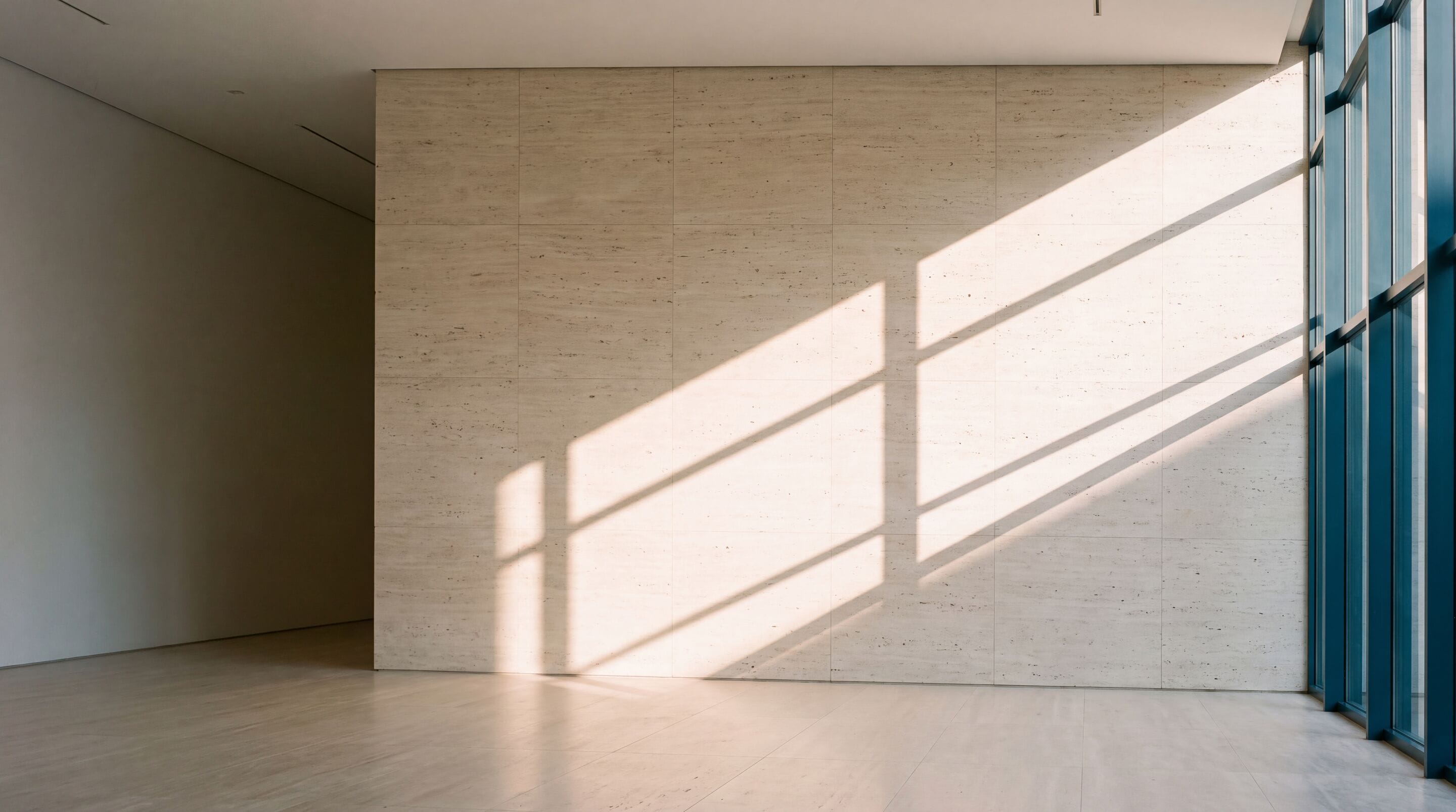 Muro de piedra clara con la sombra de un ventanal a la luz de la tarde